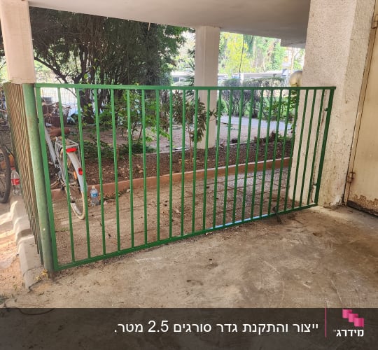 גדר ושער ברזל ממתכת בצבע ירוק בחזית מבנה